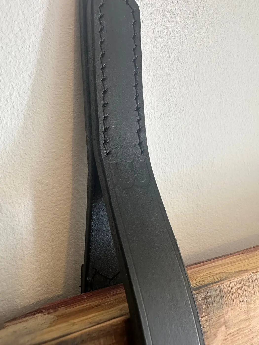 Détail d’une attache en cuir noir cousue main, fabriquée à quelques mètres de l’atelier en Côte de Nuits