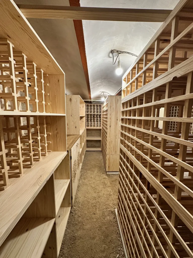 Allée centrale d’une cave à vin de 25 m² en Saône-et-Loire, rayonnages toute hauteur en bois massif