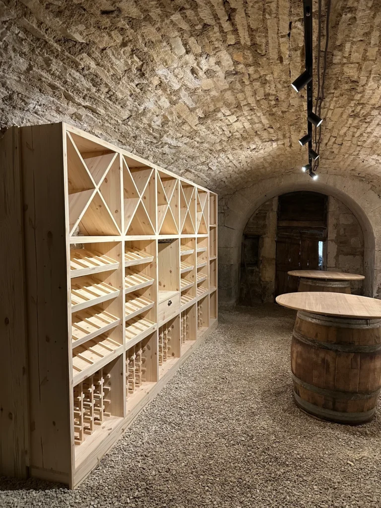 Rangement de cave à vin sur mesure sous voûte ancienne en Côte-d’Or, casiers en X et fût-plateau