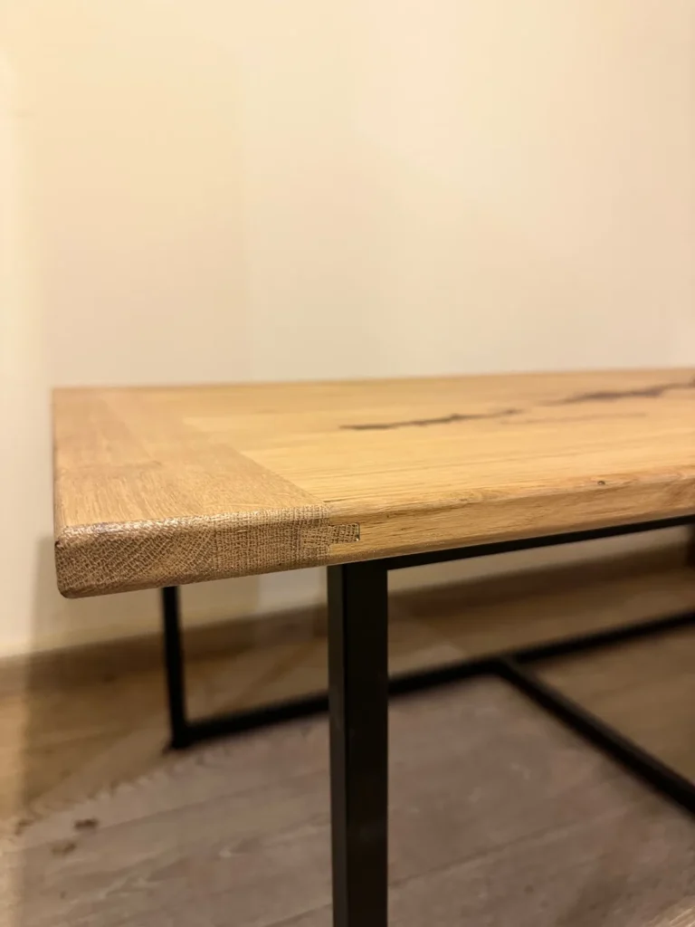 Détail du plateau en chêne massif et du pied métal noir d’une table basse sur mesure