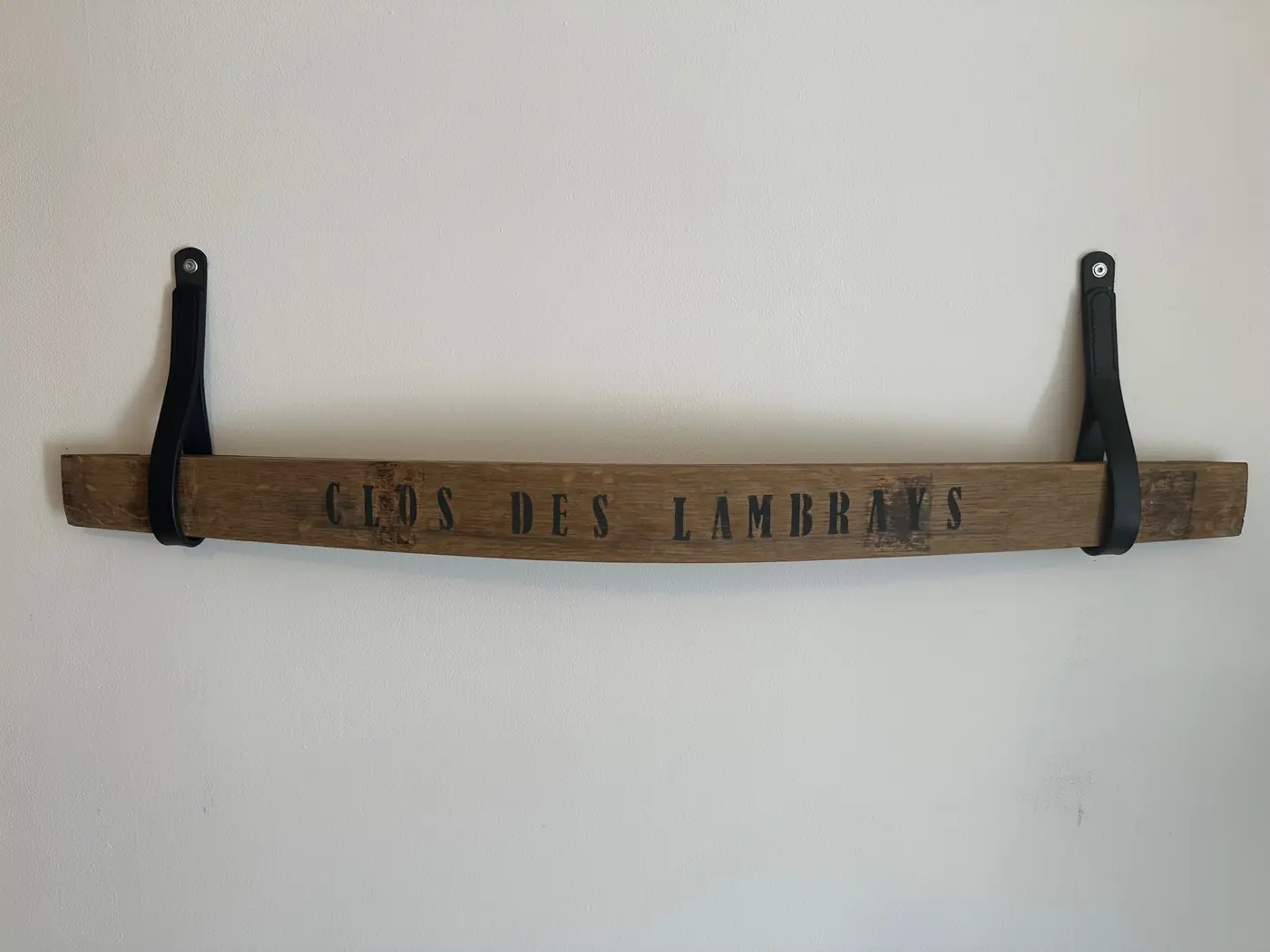 Douelle de tonneau peinte Clos des Lambrays accrochée au mur par deux attaches en cuir noir