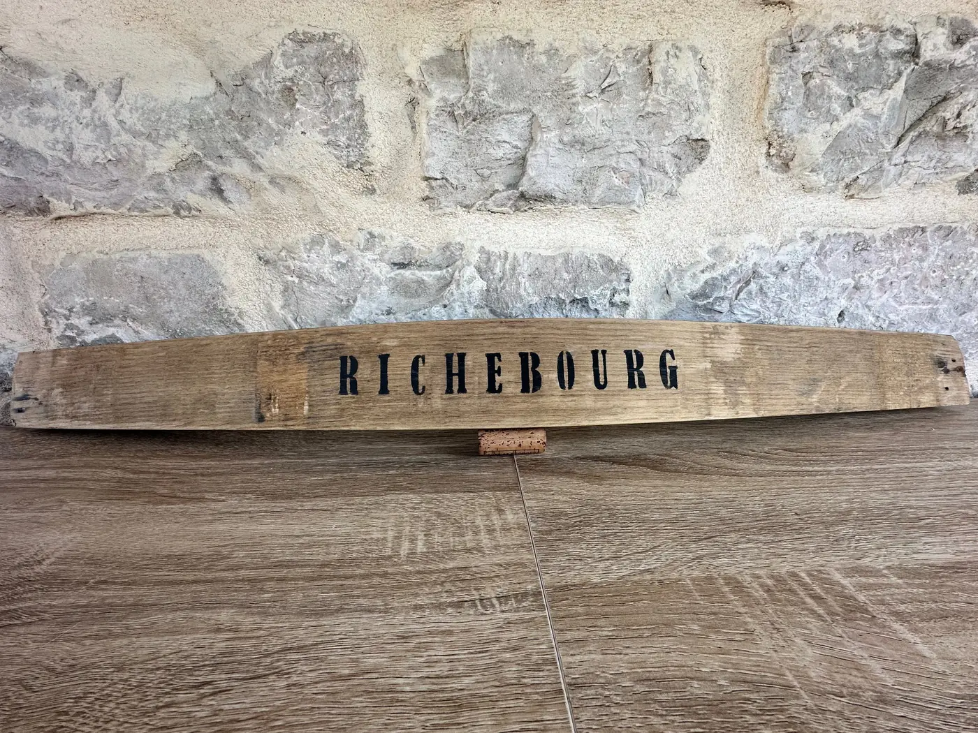 Douelle de tonneau peinte Richebourg posée contre un mur en pierre de Bourgogne