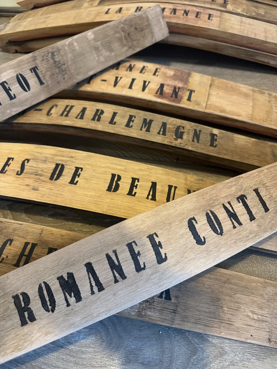 Douelles de tonneau peintes Romanée-Conti et Corton-Charlemagne empilées dans l’atelier du menuisier